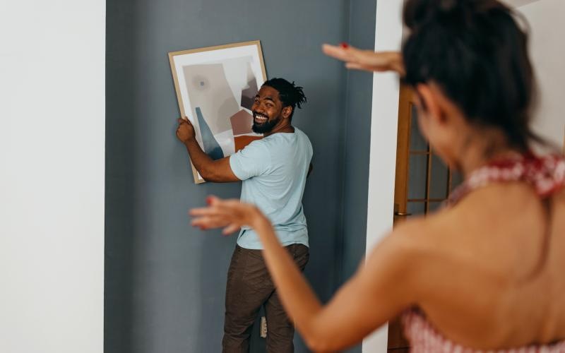 man and woman hanging a picture on a wall