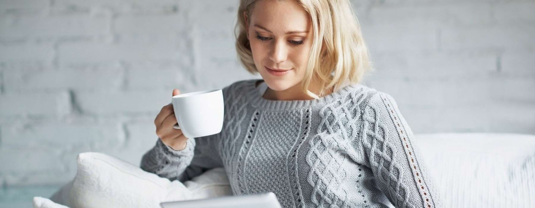 a woman holding a cup and a tablet