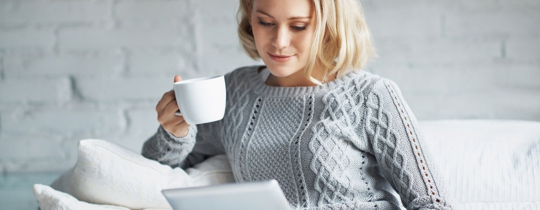 a woman holding a cup and a tablet