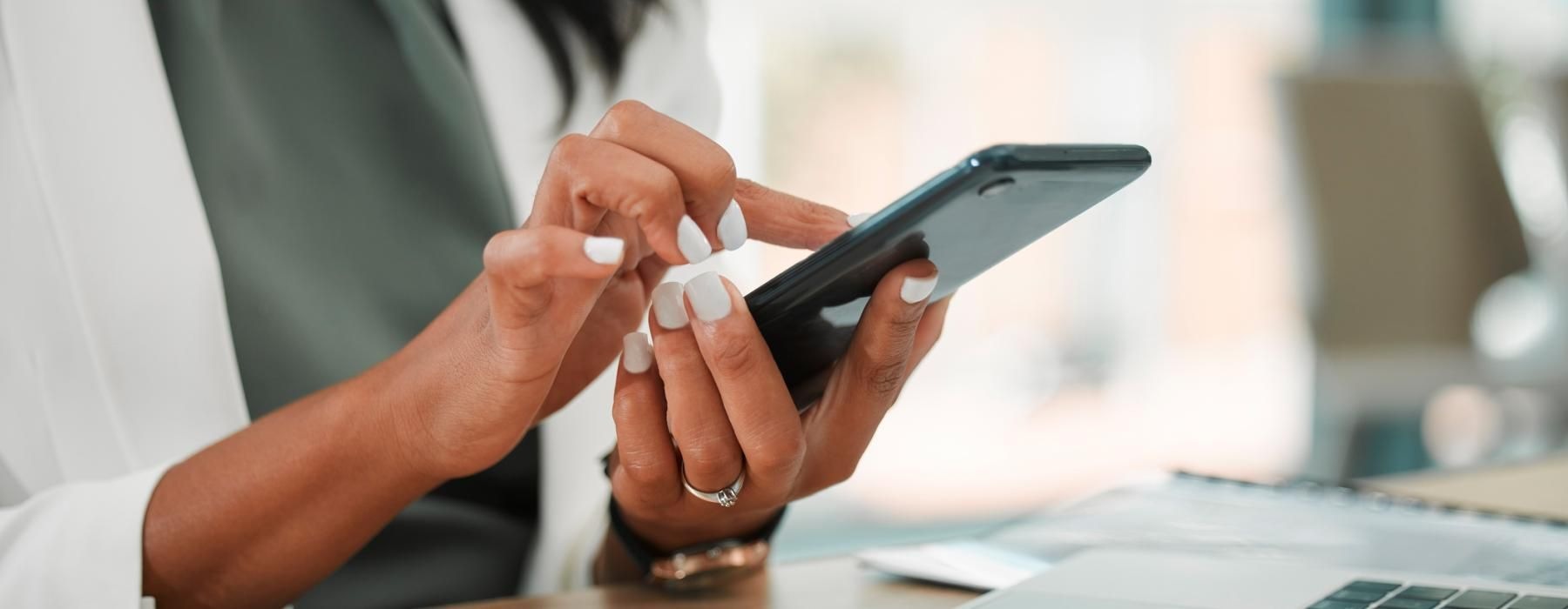 woman texting next to laptop