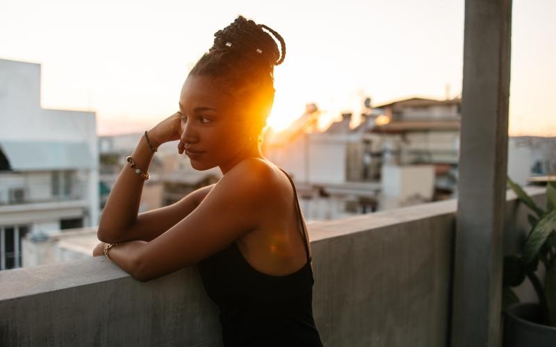 a woman leaning balcony wall looking at the city